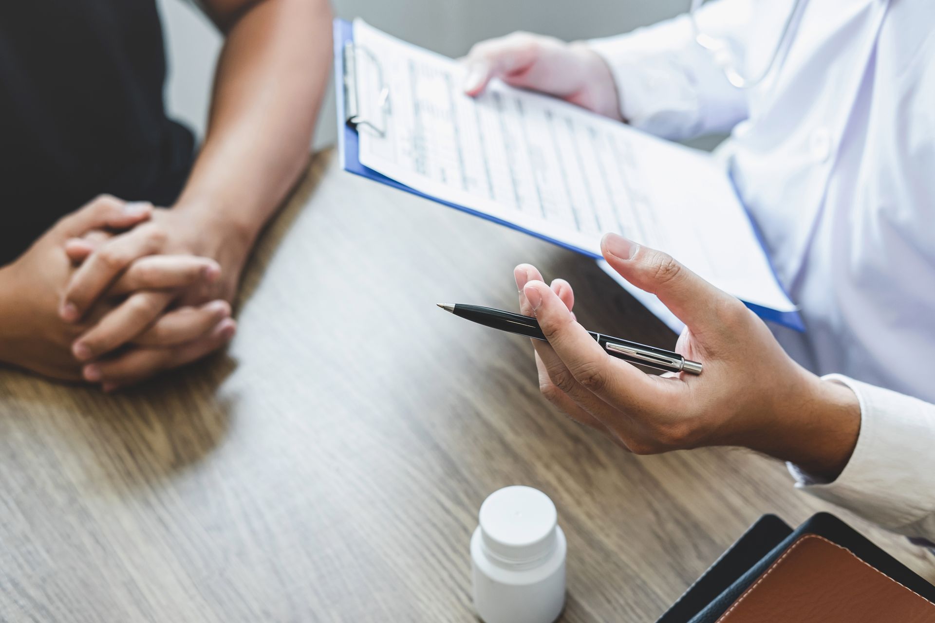 midsection-doctor-writing-prescription-patient-table
